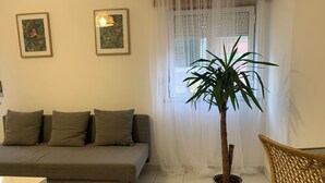 A living room with a sofa, a potted plant, a wicker chair, and a table. - Vintage Chiado with Terrace (Lisboa)