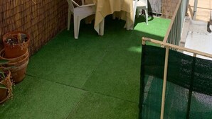 A small outdoor patio with a table and chairs, surrounded by a bamboo fence, and green artificial turf flooring. - Vintage Chiado with Terrace (Lisboa)