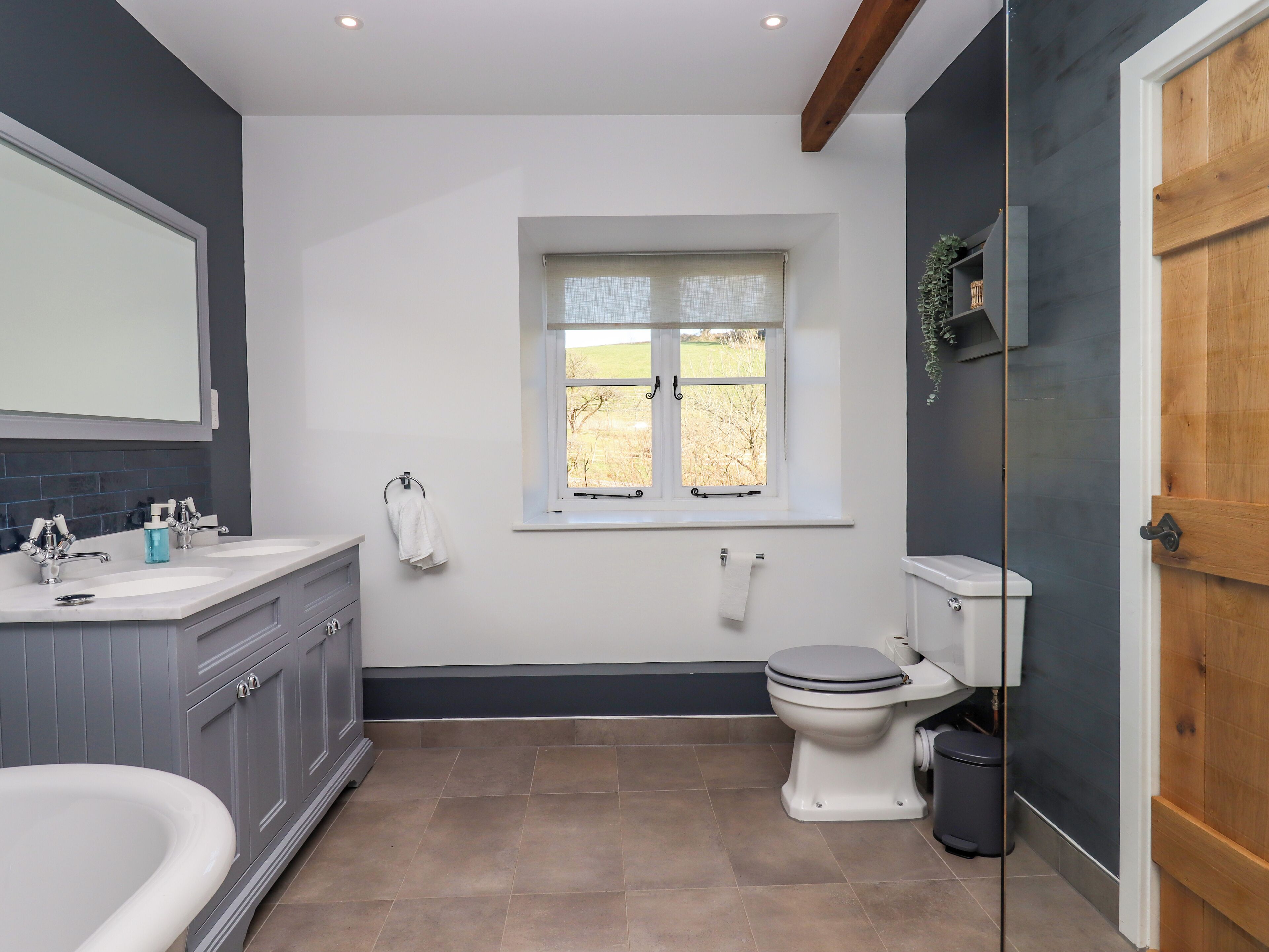 A modern bathroom with a bathtub, a toilet, and a window.