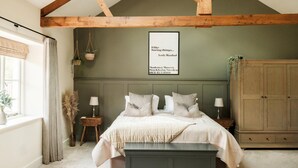 A bedroom with a bed, bedside tables, a bench, a wardrobe, and a framed quote on the wall. - Lower Well Farm House (Totnes)