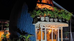 A building with a triangular roof and a covered outdoor area with plants. - Bungalow Arenal Dream View / Jacuzzi and hot springs (Palma)