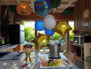 Eine Küche mit Esstisch, festlich gedeckt, mit Luftballons, einer Torte und verschiedenen Speisen.