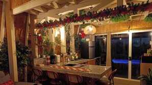 A kitchen with a bar area, equipped with a refrigerator, sink, and bar stools. - Bungalow Arenal Dream View / Jacuzzi and hot springs (Palma)