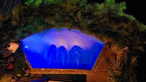 A pool with a blue illuminated edge, surrounded by tropical foliage. - Bungalow Arenal Dream View / Jacuzzi and hot springs (Palma)
