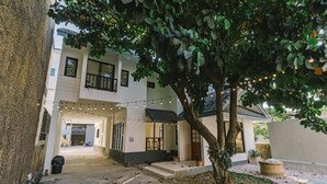 A two-story building with a covered entrance, outdoor seating area, and string lights. - Modern Family House - 4 Bedrooms 5 Mins From Old Town With Gallery - Deja Home (Chiang Mai)