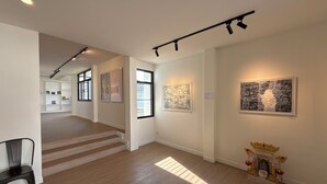 A spacious gallery with wooden floors, a staircase, and artwork on the walls. - Modern Family House - 4 Bedrooms 5 Mins From Old Town With Gallery - Deja Home (Chiang Mai)