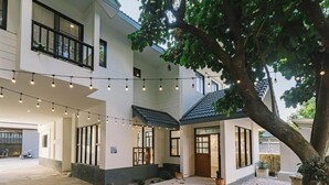 A two-story building with a covered patio area, string lights, and a tree. - Modern Family House - 4 Bedrooms 5 Mins From Old Town With Gallery - Deja Home (Chiang Mai)