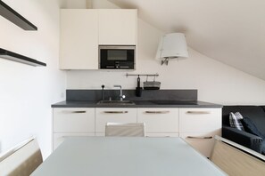 A compact kitchenette with a microwave, sink, and storage cabinets.
