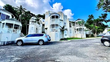 A multi-story building with a central courtyard, surrounded by palm trees and parked cars.