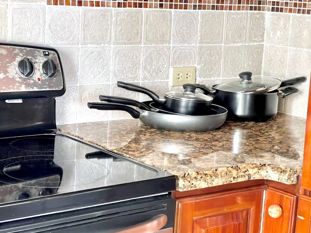 A kitchen with a black stove, granite countertop, and a tiled backsplash.