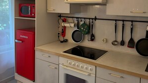 A compact kitchen with a microwave, oven, and a hanging pot rack. - Apartment 'Ferienwohnung Rothentor2' with Private Terrace and Wi-Fi (Dorf Mecklenburg)