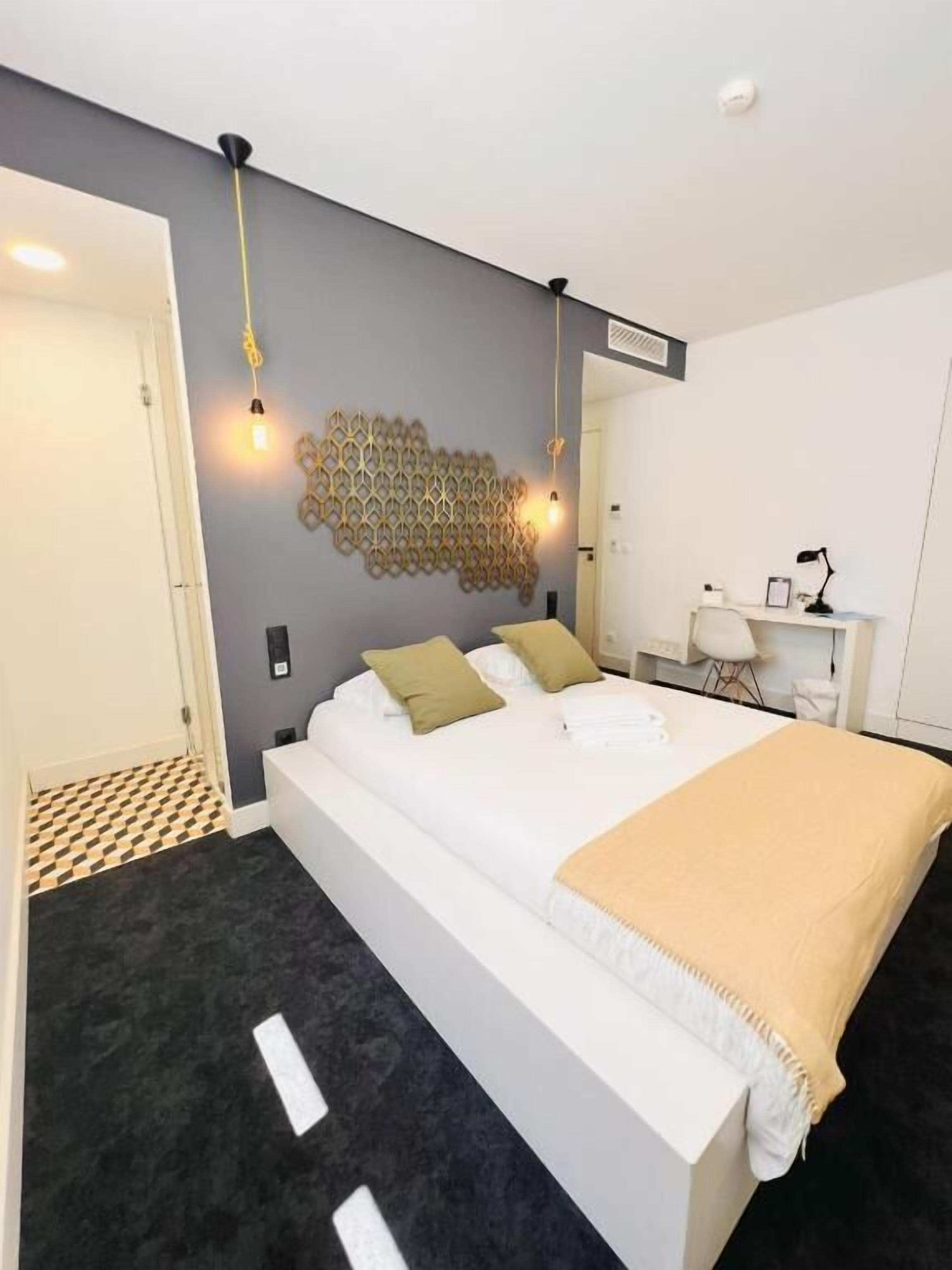 Ein modernes Schlafzimmer mit einem großen Bett, einem Schreibtisch und einem Wandkunstwerk.