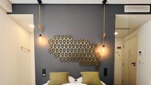A hotel room with a bed, two bedside lamps, a geometric wall decoration, and a door to the right. - Villa Rossio (Aveiro)