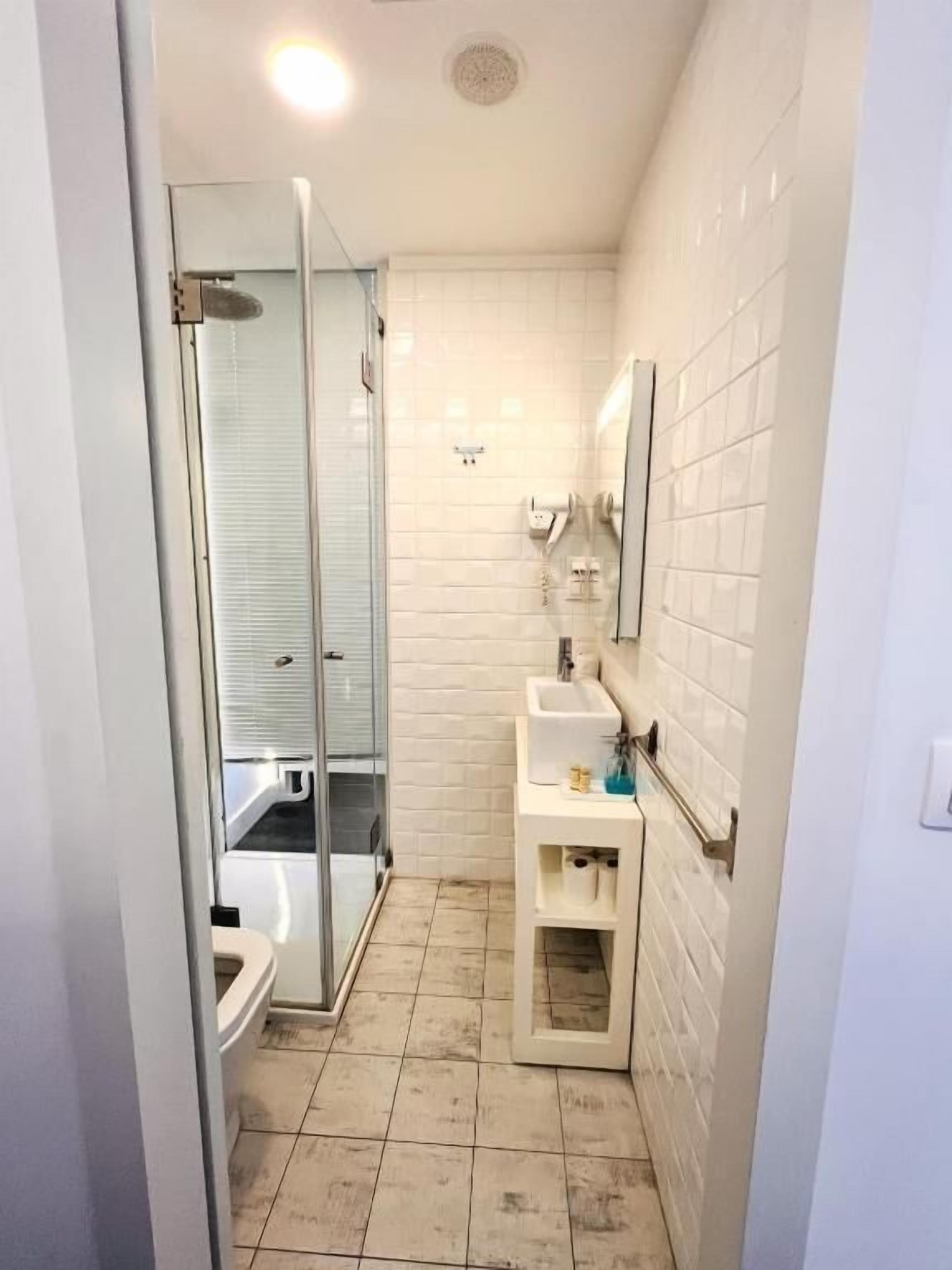 Une salle de bain compacte avec une douche à parois de verre, des toilettes et un lavabo avec un miroir au-dessus.