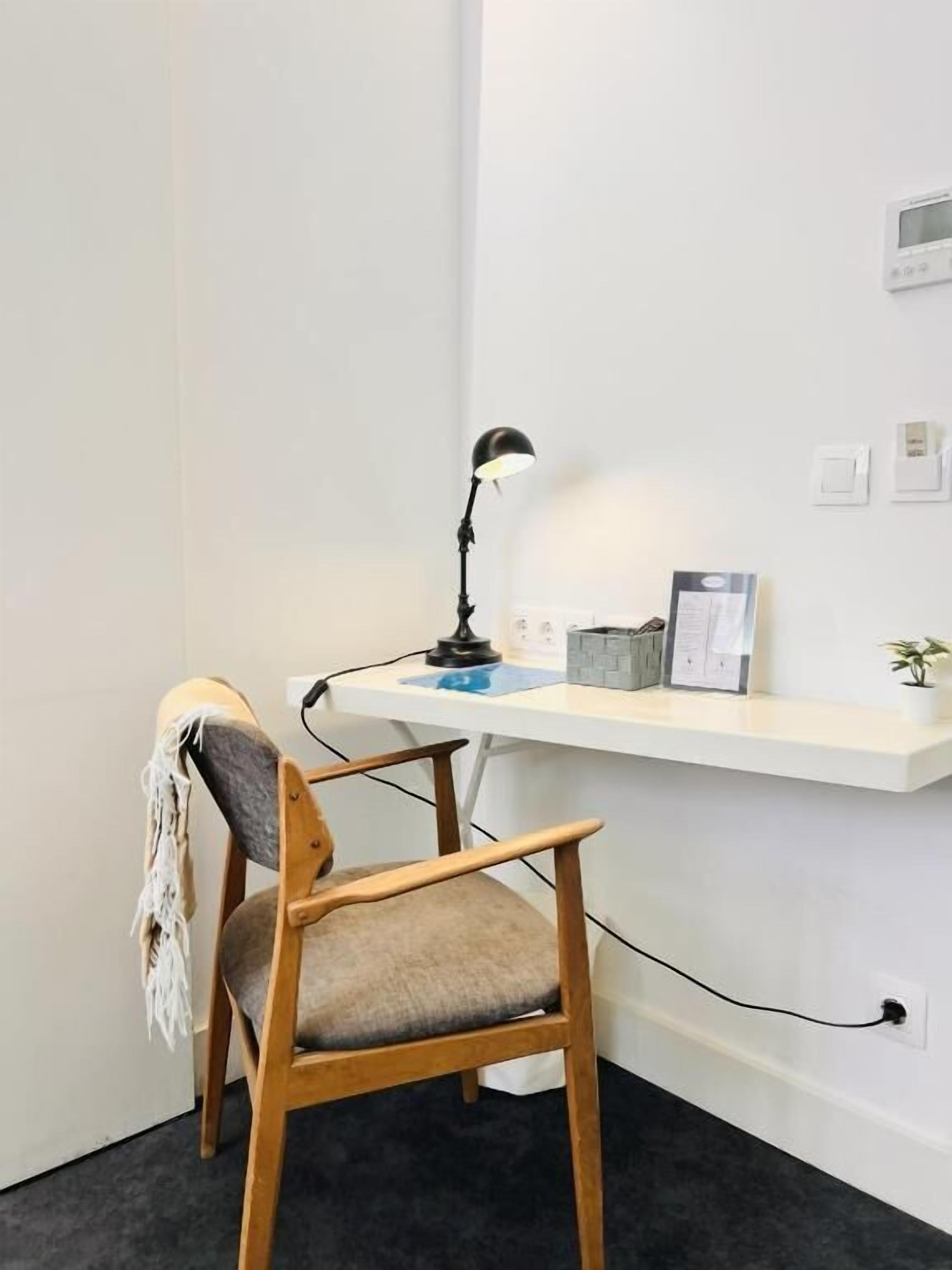 Een werkplek met een bureau, stoel, lamp en wanddecoratie.