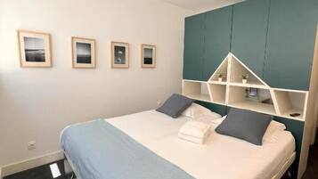 Un dormitorio moderno con una cama grande, una pared de acento color turquesa y una unidad de estanterías empotradas.