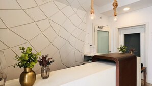 A reception desk with a geometric wall design, a wooden reception desk, and a hanging light fixture. - Villa Rossio (Aveiro)