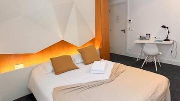 Una habitación de hotel moderna con una cama grande, un escritorio y una silla.