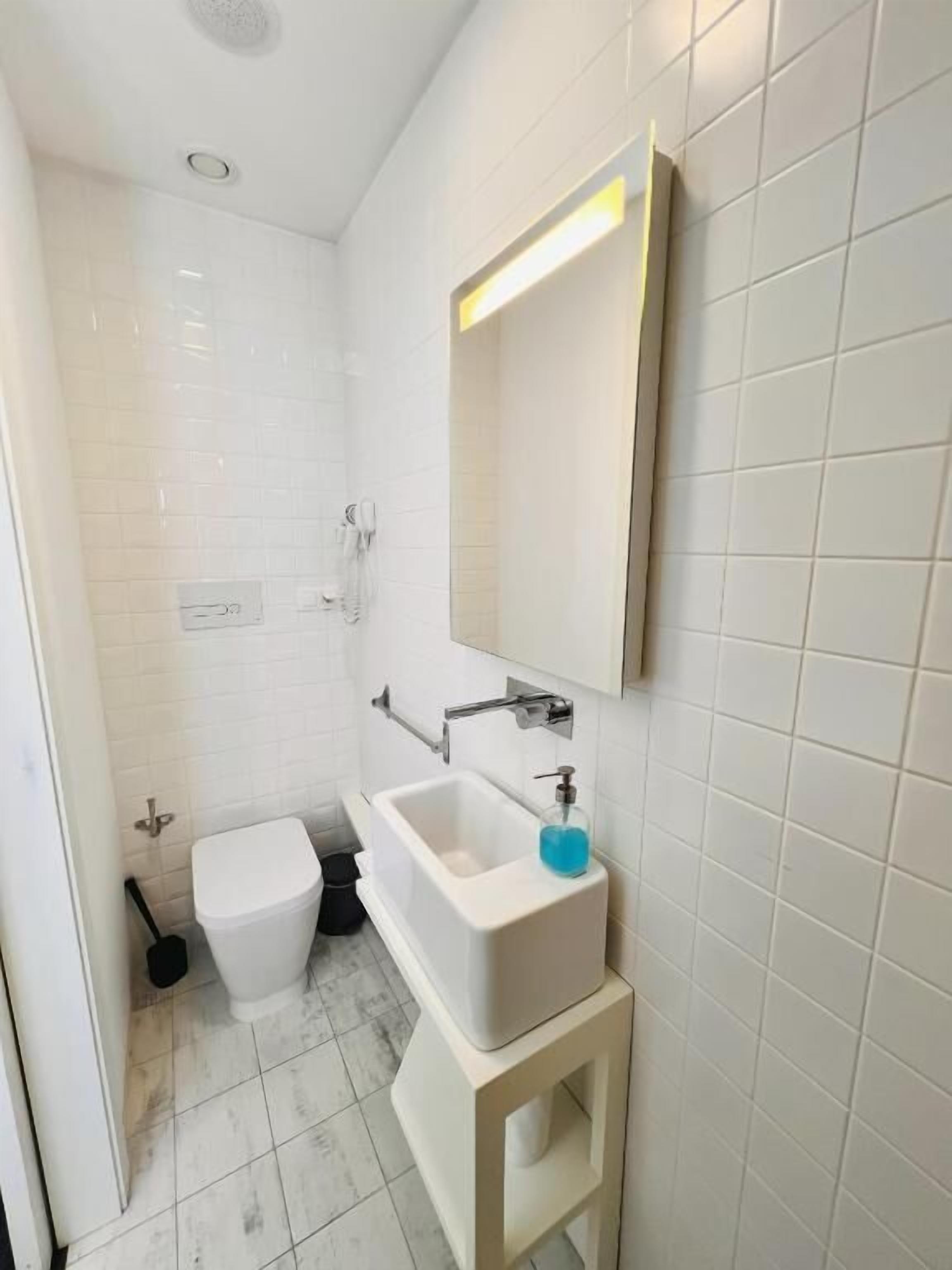 Une salle de bain moderne avec un lavabo blanc, un miroir et des toilettes.