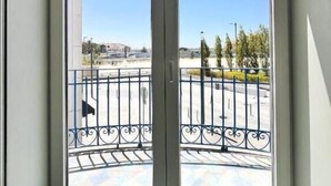 A view through a glass door with a metal railing, leading to an outdoor area with a tiled floor and a clear sky. - Villa Rossio (Aveiro)
