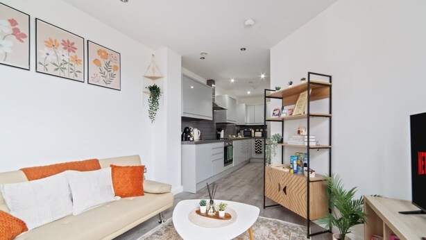 A modern living room with a sofa, coffee table, and a kitchen in the background. - The Copper Nest 2BR City Centre (Leicester)