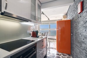 A modern kitchen with a large window, a built-in oven, and a unique orange refrigerator.