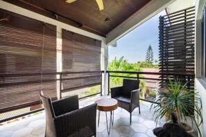 A balcony with wicker furniture, a small round table, and a potted plant. - Samaya Luxury Villa - Melaka (Melaka Tengah)
