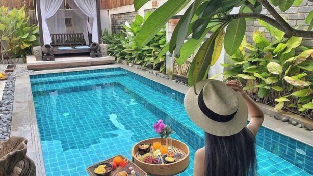 Zona junto a la piscina con un conjunto de asientos y una bandeja de frutas y aperitivos.