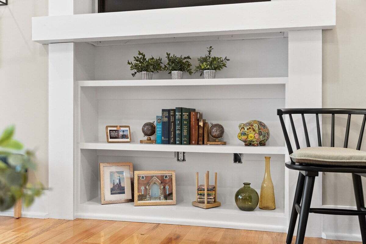 Une bibliothèque blanche agrémentée d’objets décoratifs et de livres.