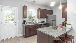 A modern kitchen with dark wood cabinets, a granite countertop, and a built-in island with stools. - 19th Hole Haven in Sango 1625 Golf Club, #601 (Clarksville)