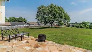 A backyard with a stone patio, a metal grill, and a large tree. - Magnolia Summary:<br>Hil (Clarksville)