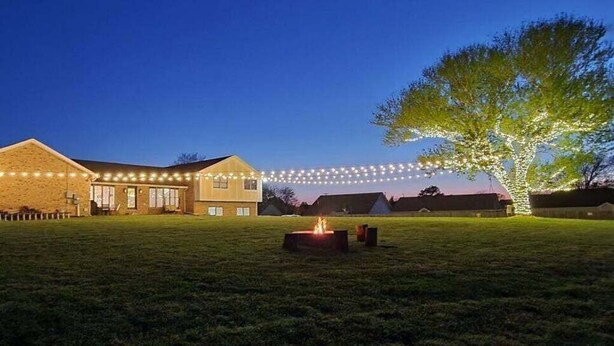 A house with a fire pit in the yard, surrounded by string lights. - Magnolia Summary:<br>Hil (Clarksville)