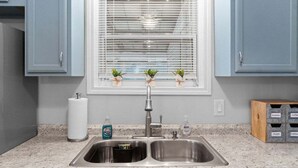 A kitchen with a double sink, a window with blinds, and a countertop with a paper towel holder and a soap dispenser. - Gratton Granny 979 Gratton Rd (Clarksville)
