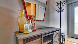 Une console en bois agrémentée de vases en verre et d’un miroir.