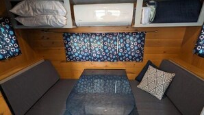 Ett kompakt vardagsrum med ett bord i mitten, bekväma sittplatser och en vägg med ett mönster.