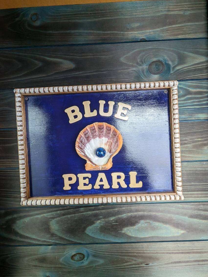 A framed sign with the words "BLUE PEARL" and a seashell.