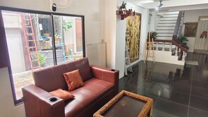 Un'ampia zona giorno con un divano in pelle, un tavolino da caffè in vimini e vista all'esterno tramite un'ampia finestra.