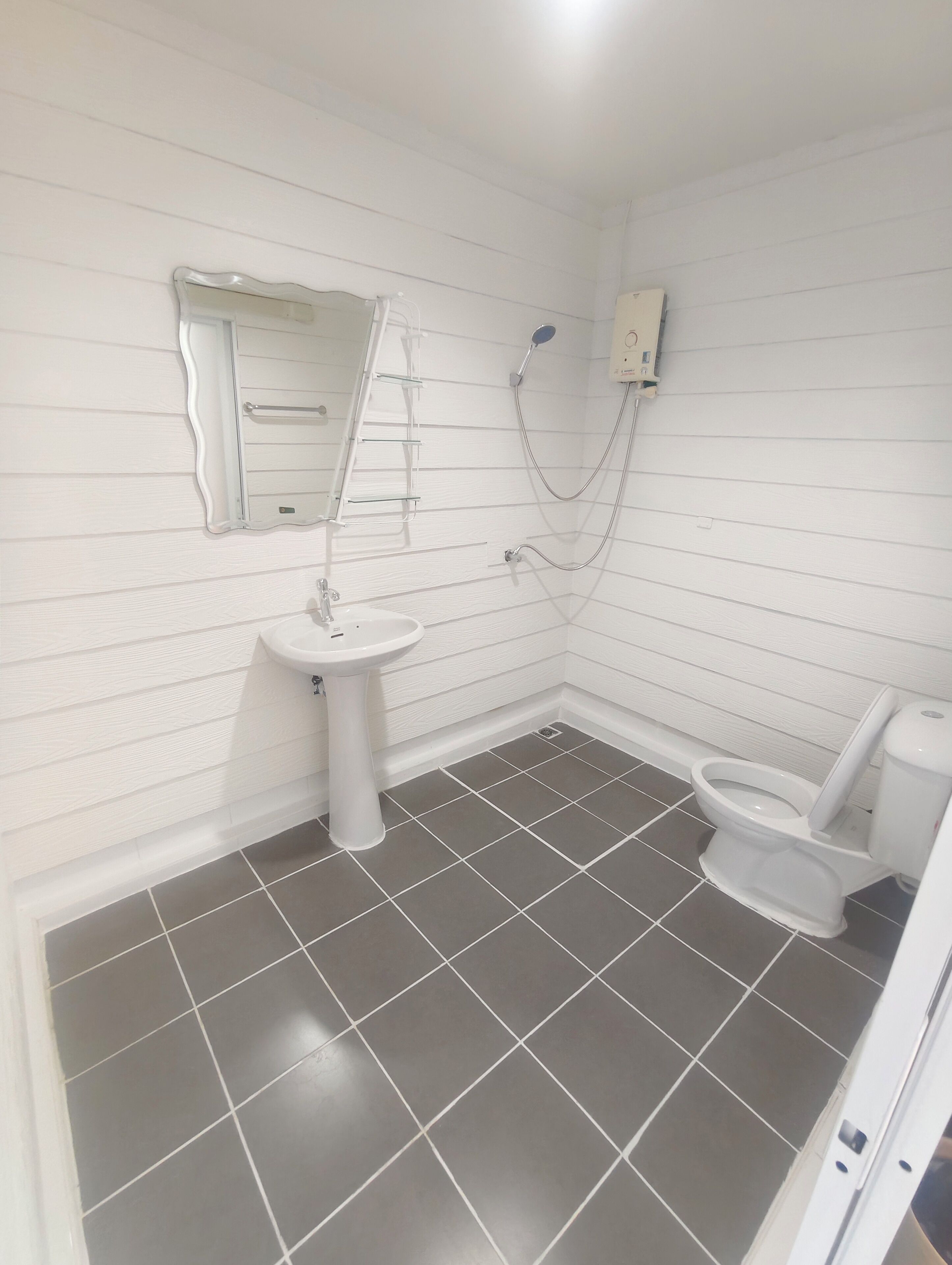 Une salle de bain avec un lavabo blanc, des toilettes et une douche.