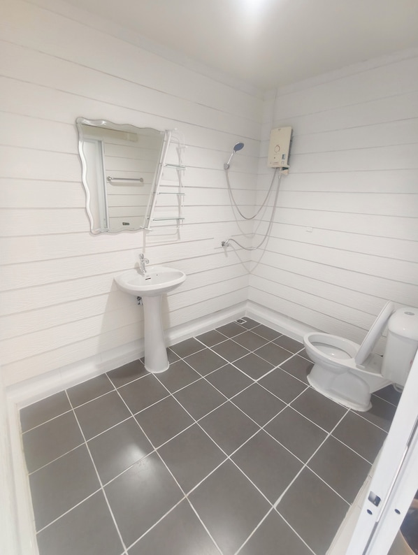 A bathroom with a white sink, a toilet, and a shower. - Kamala Beachside (Kamala)