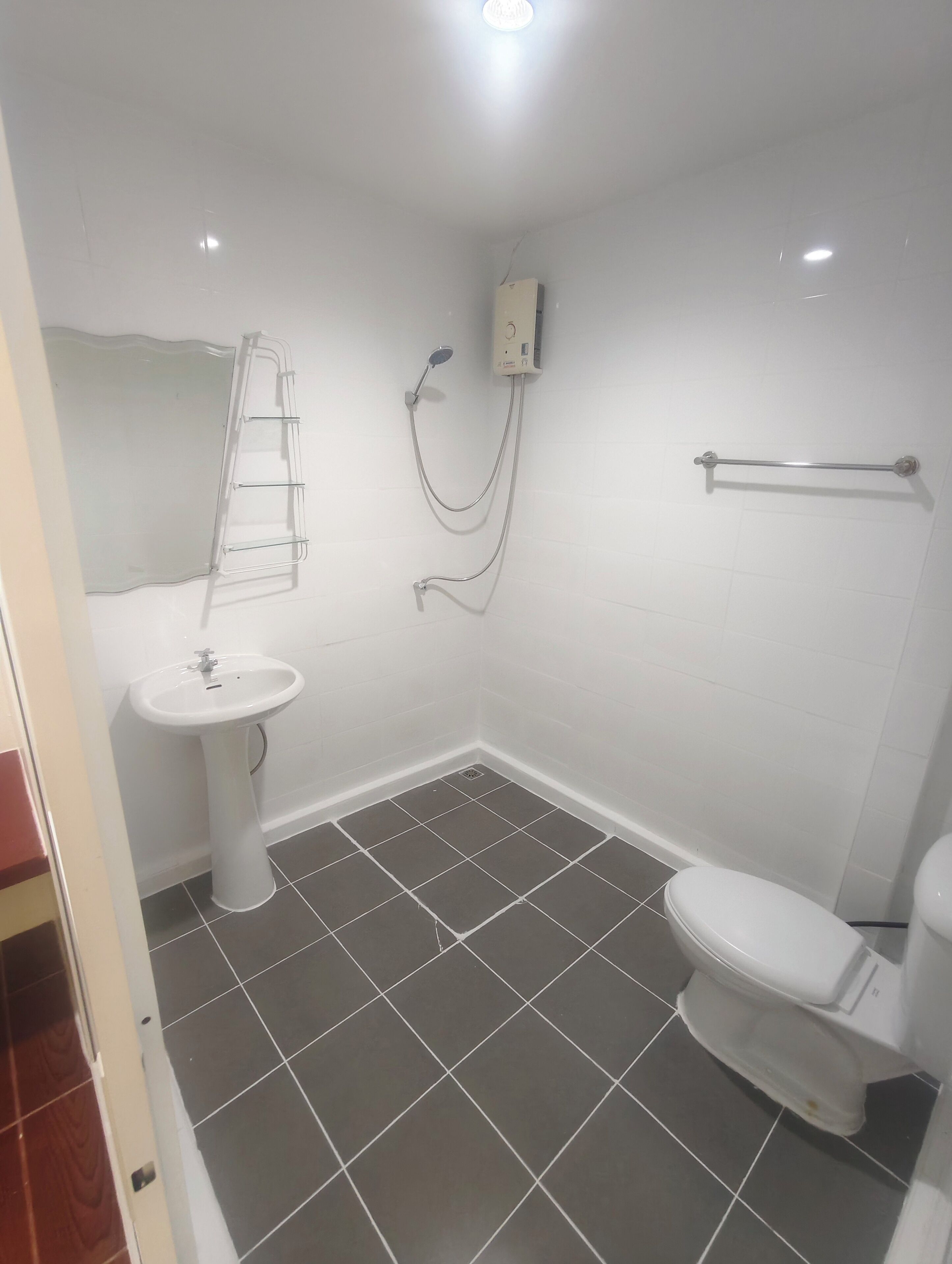 A small bathroom with a white sink, a toilet, and a shower unit.