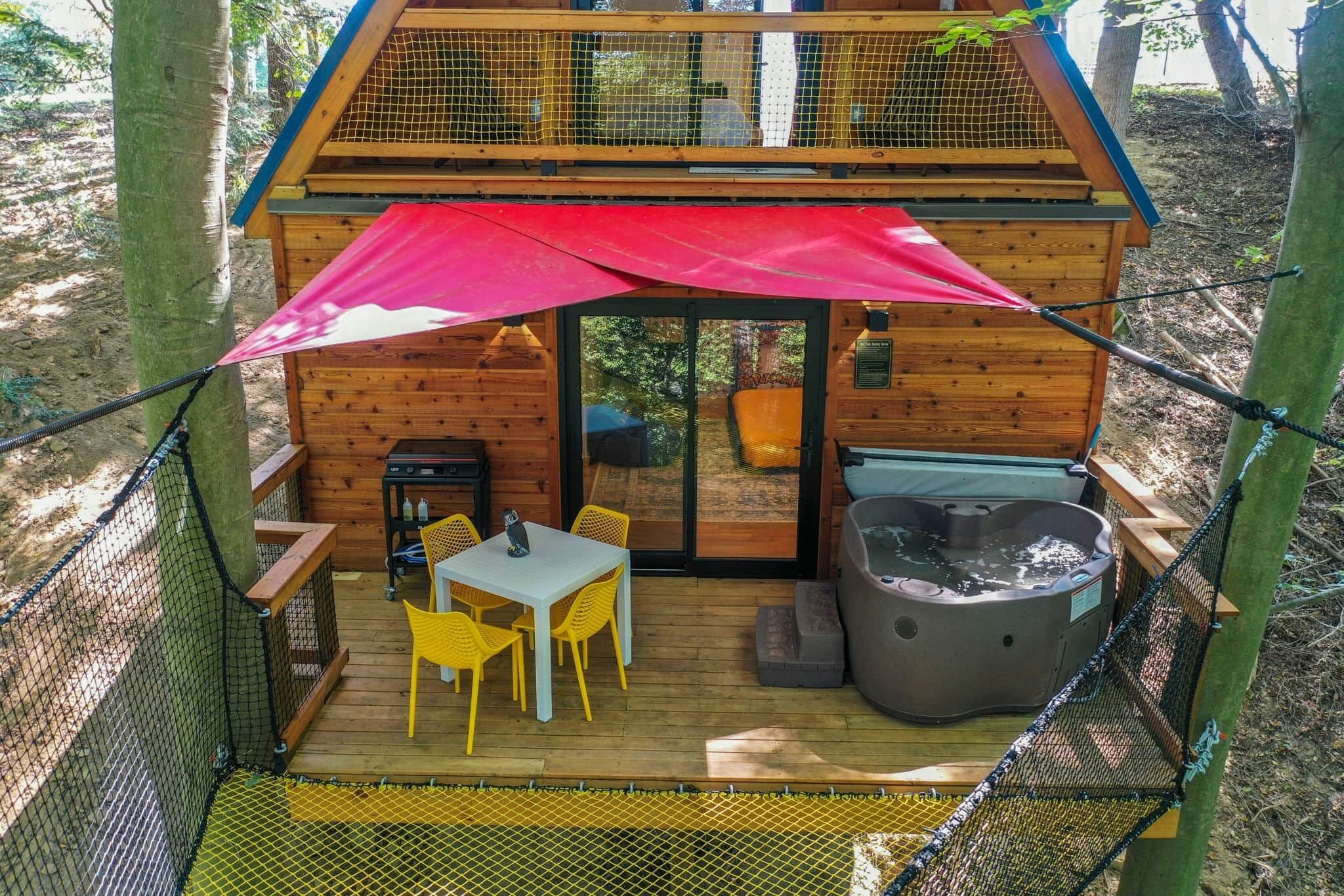 Une cabane en bois dotée d’une terrasse, d’un bain à remous et d’une table avec des chaises.