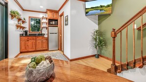 A modern kitchen with wooden cabinets, a built-in microwave, and a large window. - The Country Club Treehouse (Rockbridge)