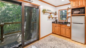 A modern kitchen with wooden cabinets, a built-in microwave, and a refrigerator. - The Country Club Treehouse (Rockbridge)