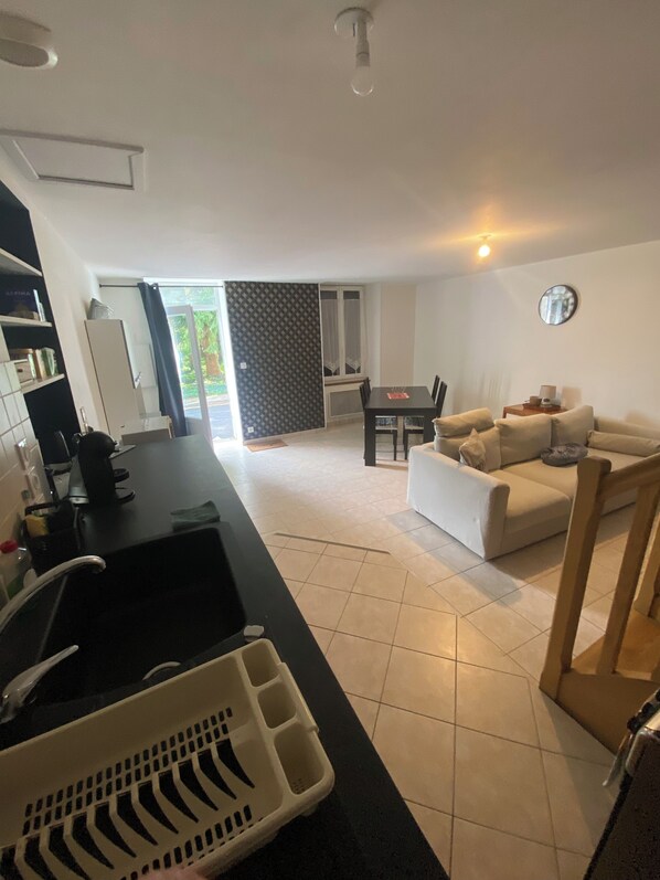 A modern kitchen with a black countertop, a sink, and a white storage basket. - Cottage in quiet village (Chef-Boutonne)