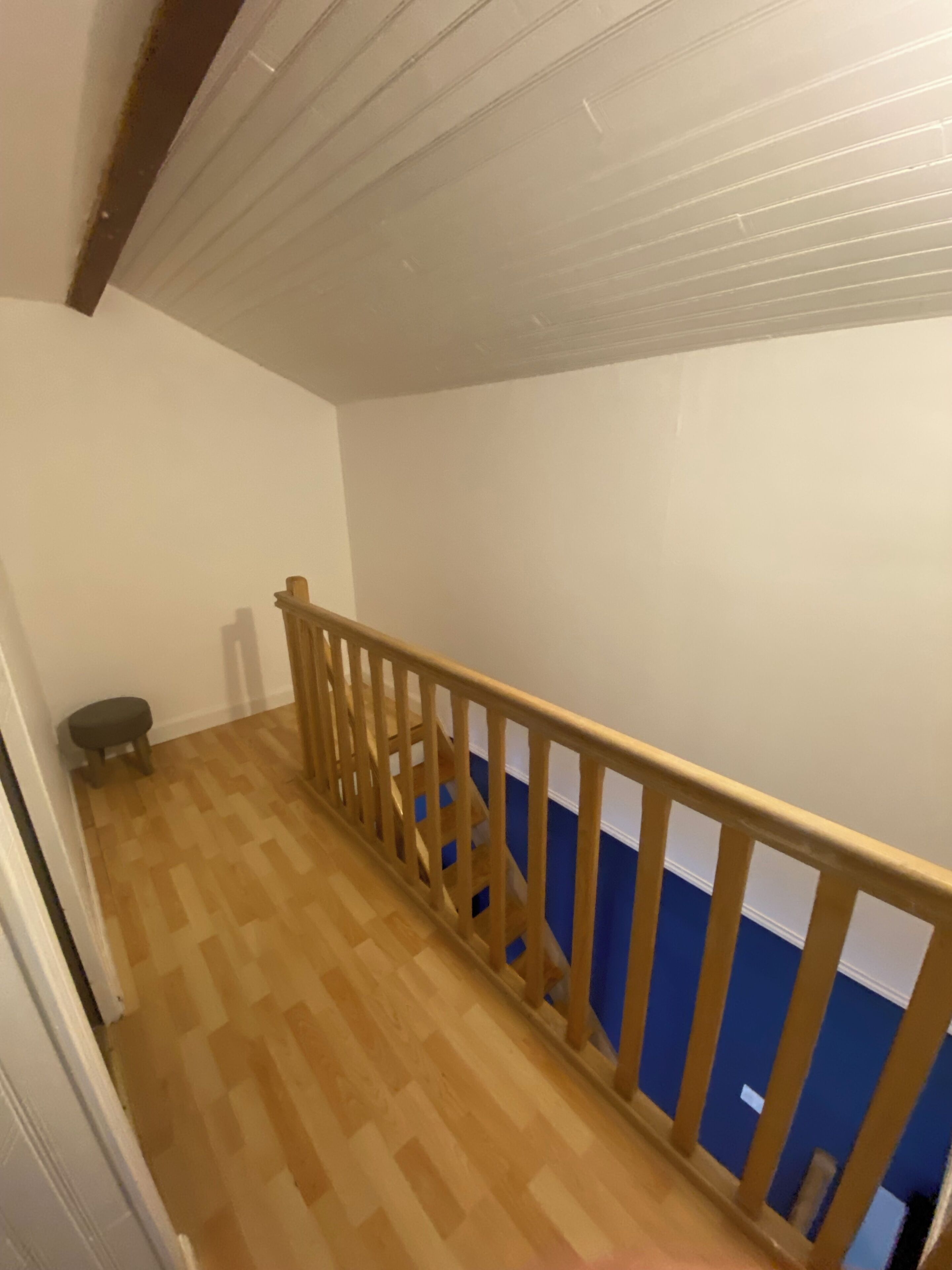 Un escalier en bois avec un mur bleu en haut.