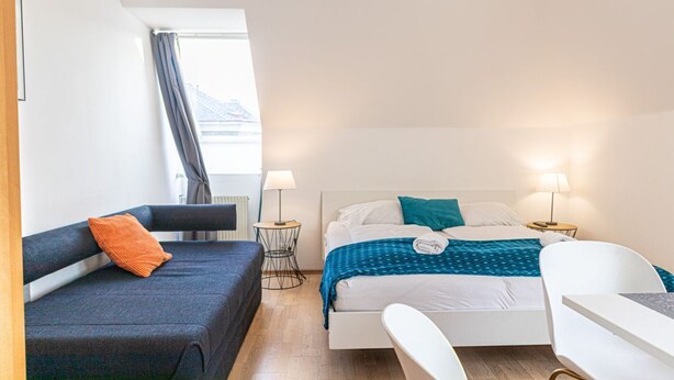 A hotel room with a bed, a sofa, a desk, and a chair.