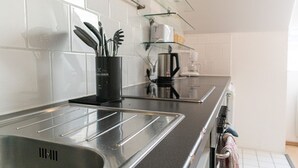 A modern kitchen with a stainless steel sink, a coffee maker, and glass shelves.