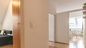 A modern interior with a wooden door, a sofa, a dining area, and a staircase.