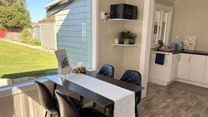 A dining area with a table, chairs, and a view of the backyard. - The Nest on Till (Oamaru)