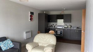 A compact living space with a kitchenette, a sofa, and a chair. - Apartment - Sleeps 4, Pets Allowed & Parking (Salford)